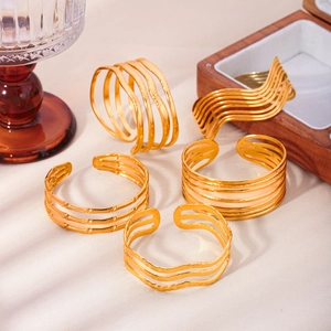 Golden multi-layer textured open bangles set in stainless steel displayed on beige fabric