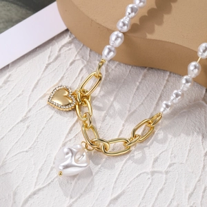 Detail of baroque pearl necklace with golden heart pendant and mixed chain link design