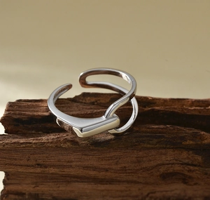 Macro shot of silver geometric minimalist open ring on a textured dark wood block