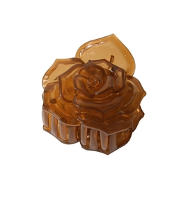 Détail d'une pince à cheveux rose en résine ambrée avec pétales multicouches en relief