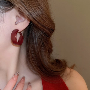 Close-up of deep red enamel C-shaped earrings worn by a model in a vintage style shot