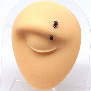 Macro view of silver fist eyebrow piercing with black bead on realistic model