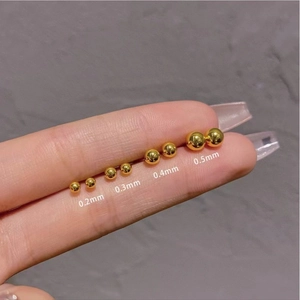 Mini gold frosted stud earrings in four sizes displayed on a fingertip for scale