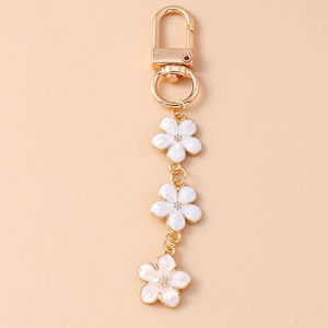 Close-up of golden cherry blossom keychain with white enamel flowers and lobster clasp