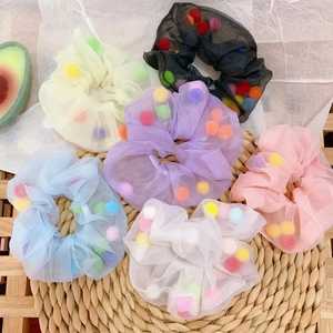Detail of colorful organza scrunchies filled with mini plush balls on straw mat
