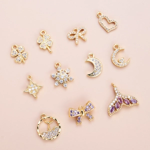 10 styles of 18K gold plated charms with zircons for DIY bracelet making on pink background