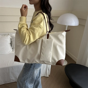 Large cream oxford tote bag with brown leather handles worn by a model in a bright room