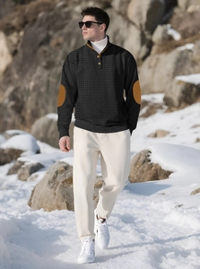 Macro detail of men's black waffle knit sweater with contrasting brown elbow patches