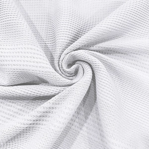 Macro shot of white waffle knit fabric texture showing breathable jacquard polo shirt material