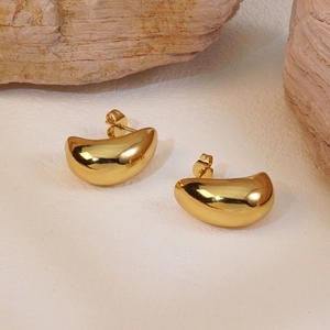 Detailed close-up of shiny gold bean-shaped titanium steel stud earrings on natural stone