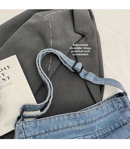 Detail of adjustable shoulder strap on light blue denim bag with black buckle