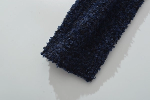 Dettaglio del tessuto a maglia blu scuro con trame e motivi intrecciati definiti
