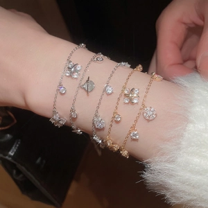 Elegant layered zircon bracelets featuring planet and flower charms on a model's wrist