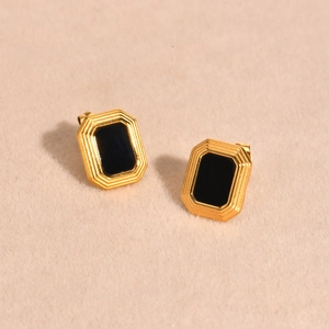 Macro detail of gold vintage rectangular earrings with black onyx inlay on beige velvet