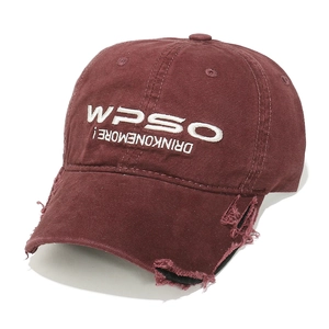 Close-up of distressed wine red baseball cap with white embroidery and ripped brim detail