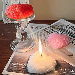 Handcrafted rose embossed heart candles in red, pink and white on a vintage wooden desk