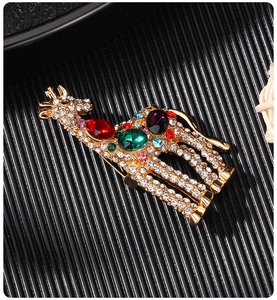 Macro shot of gold-plated giraffe brooch with colorful rhinestones on black wavy surface