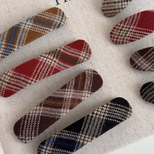 Elegant rectangular plaid fabric hair clips in assorted retro colors on burlap background