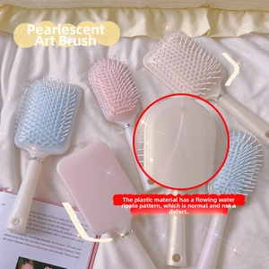 Detailansicht der perlmuttfarbenen Luftkissen-Haarbürsten in Blau, Rosa und Beige Tönen