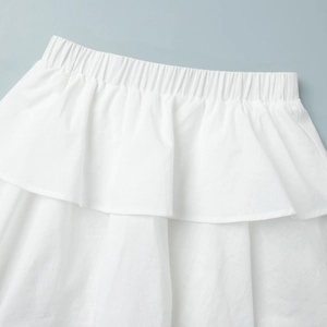 Detail of white linen skirt showing elastic pleated waist and tiered ruffle hem design