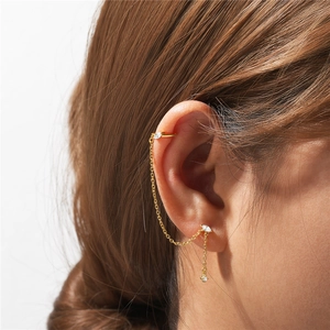 Close-up of gold chain earring with white marquise zircons and ear cuff on model