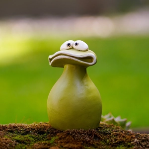Close-up of funny frog garden ornament with large eyes and wide mouth on mossy ground
