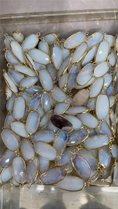 Close-up of bulk natural opal and amethyst crystal faceted oval pendants with gold plating
