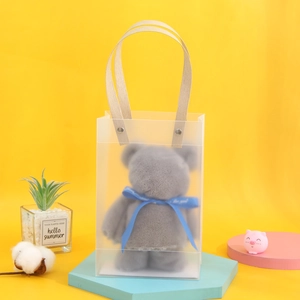 Gray plush bear towel in a frosted gift bag with blue ribbon on yellow background