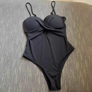 Detailed view of black ribbed one-piece swimsuit featuring front twist knot and hollow cutout