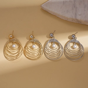 Elegant multi-layered gold and silver geometric pearl hoop earrings on beige surface