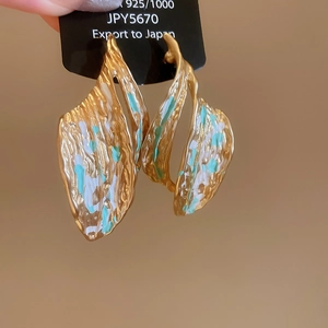 Macro detail of leaf-shaped earrings with hammered texture and colorful enamel coating