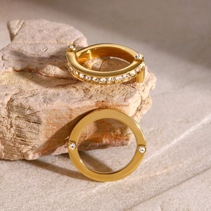Detail of gold stainless steel rings with sparkling cubic zirconia on natural stone
