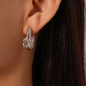 Gros plan de boucles d'oreilles en argent nouées en double C avec un design de corde tressée