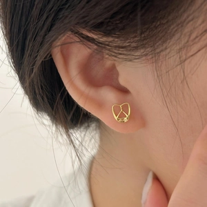 Macro side view of a gold-plated pretzel-shaped stud earring worn on the earlobe