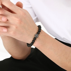 Macro detail of 8mm lava stone bead bracelet featuring a silver lion head metal charm