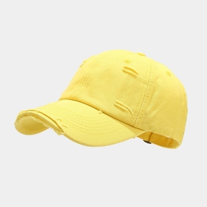 Detailed view of yellow distressed baseball cap with vintage frayed edges and torn fabric