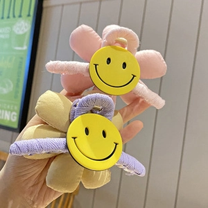 Detail of fabric flower hair claws with smile face motifs in candy pastel colors