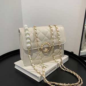 Quilted beige chain crossbody bag with pearl buckle and metal strap on display