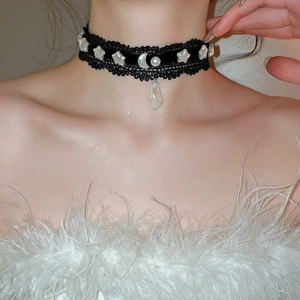 Gros plan d'un collier ras du cou en dentelle noire avec perles et pendentifs lune