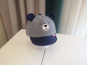 Detail showing baby sun hat with navy stripes, 3D bear ears, and cute embroidered face