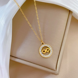 Detailed close-up of golden infinity circle pendant with crystals on a fine link chain