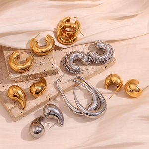 Gros plan de boucles d'oreilles gouttes dorées et argentées sur pierre texturée