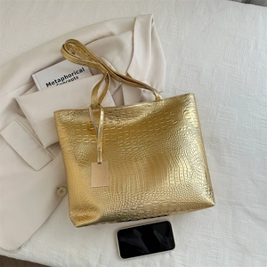 Fashionable crocodile pattern tote bag in gold PU leather for women on beige background