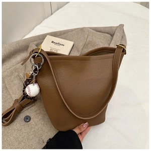 Brown lychee leather bucket bag detail with baseball pendant and soft texture