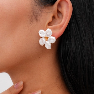 Detail view of pearl flower stud earrings with golden accents on a model ear