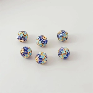 Macro detail of 18K gold plated cloisonne watermelon beads with blue enamel inlay