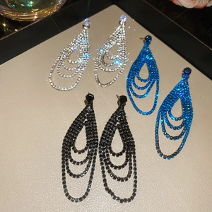 Vue macro des boucles d'oreilles à pompons en forme de goutte avec strass étincelants