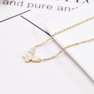 Collier en acier titane avec pendentif papillon en nacre sur un plateau blanc
