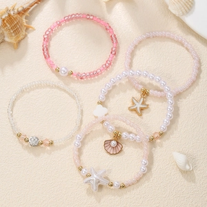 Detail of 5-piece beach bracelet set with starfish shells and colorful beads on sand