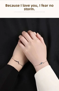 Close-up of couple bracelets with mountain and sea charms on silver chains